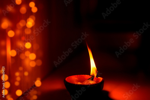 Happy Diwali Diya with bokeh background image of burning lit diya clay oil lamp with bokeh lights. Concept for Indian Hindu religious tradition, rituals festive season celebration at home.