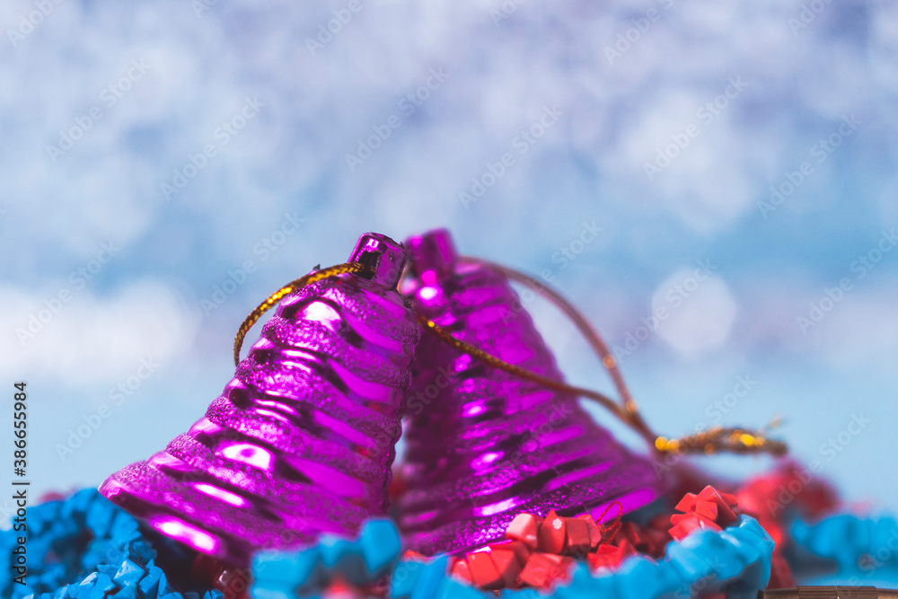 Christmas or new year card. Two lilac Christmas bells on a blue bokeh background. Selective focus.