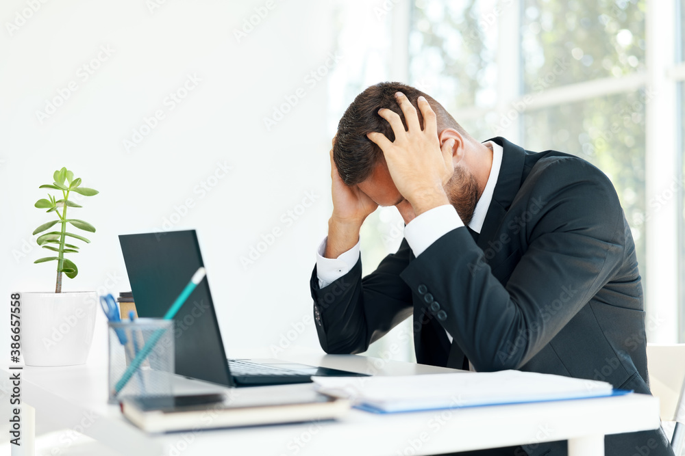 Stressed tired businessman sitting at the desk in creative office Stressed tired businessman sitting at the desk in creative office