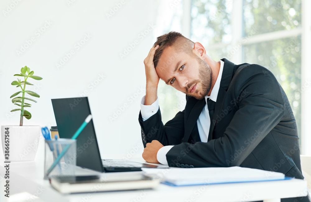 Stressed tired businessman sitting at the desk in creative office Stressed tired businessman sitting at the desk in creative office