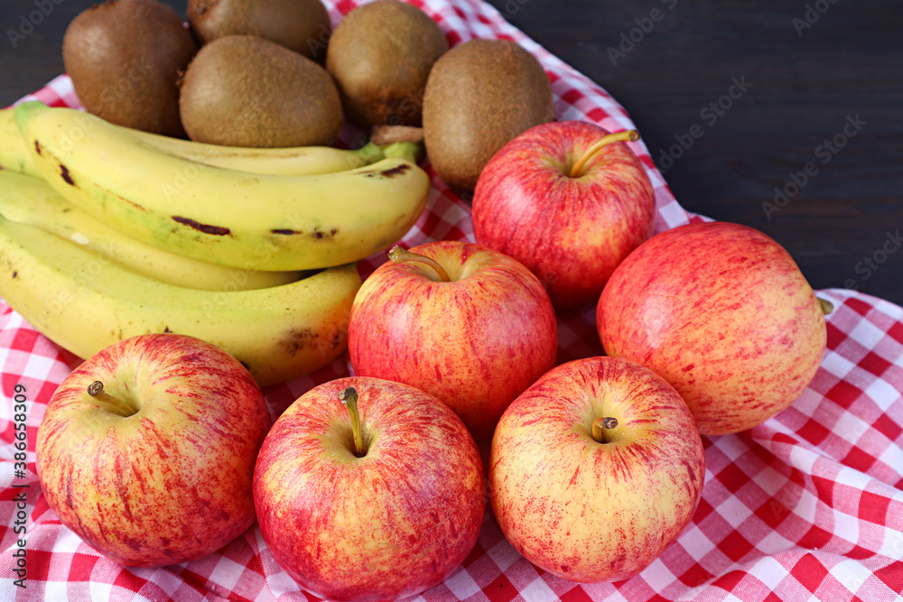 Heap of Fresh Ripe Apples, Bananas and Kiwi Fruits on Checkered Cloth for the Concept of EATING WELL Heap of Fresh Ripe Apples, Bananas and Kiwi Fruits on Checkered Cloth for the Concept of EATING WELL