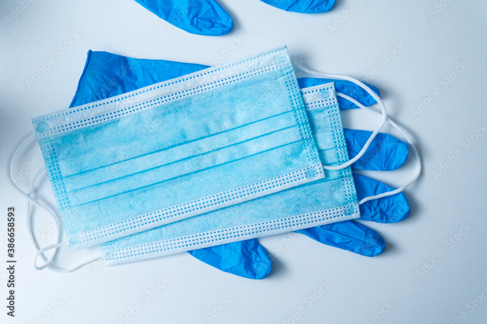 Medical mask and blue gloves on white table. Surgical mask and gloves. Virus protection concept. Healthcare and medical equipment in the hospital. Antiviral medical protection against corona virus.