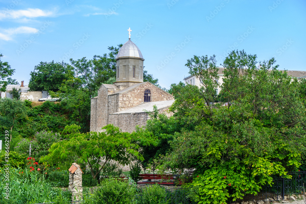 Orthodox church of John The Baptist surrounded by lush blooming garden, Feodosia, Crimea. Temple was built in XIV century by Armenians