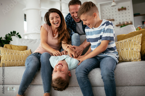 Young family enjoying at home. Mother and father tickling son.