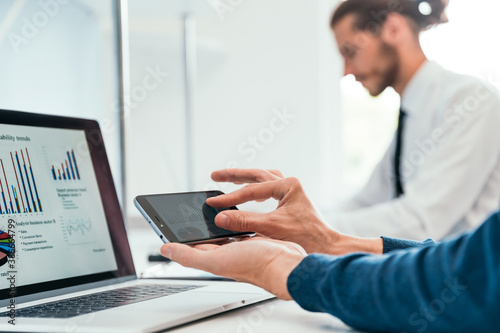 close up. employee is using his smartphone to check the financial data .