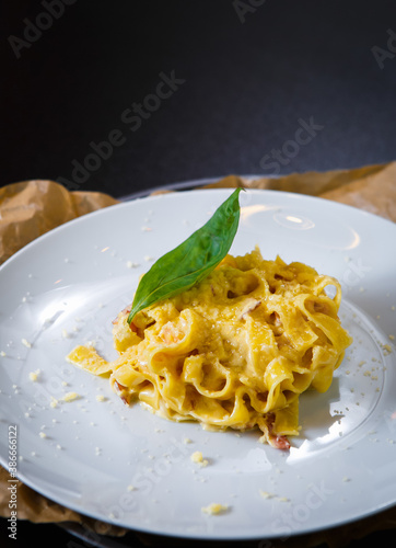 Italian pasta dish with oregano leaves served on white plate with fused parmesan cheese toping.Delicious Italian cuisine in restaurant photo