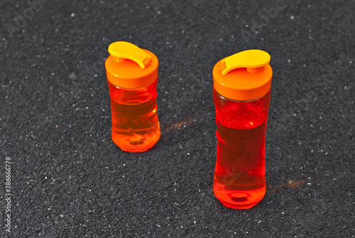 Orange water bottle on a black treadmill. The concept of a healthy lifestyle. Copy space and place for text near the bottle.