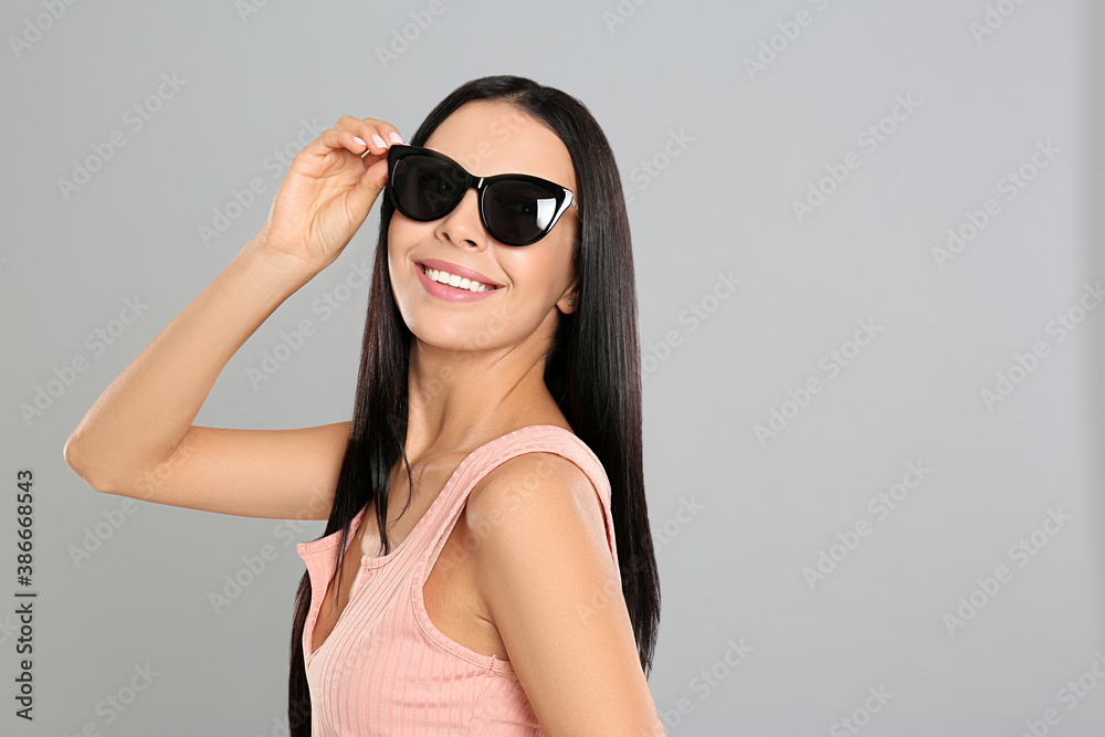 Beautiful woman wearing sunglasses on grey background Beautiful woman wearing sunglasses on grey background
