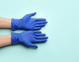 Person in medical gloves on light blue background, top view. Space for text