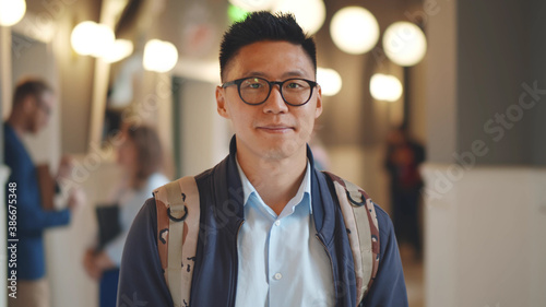 Portrait of cheerful asian male student with backpack posing indoors photo
