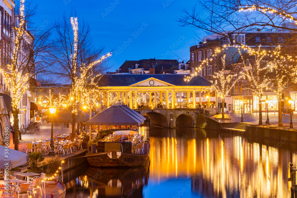 The Dutch Oude Rijn canal with bridge, historic buildings and christmas lights in the city center of Leiden
