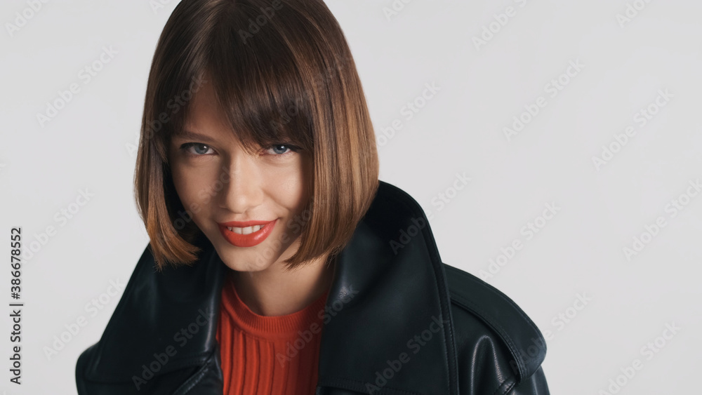 Beautiful model with bob hair and red lips confidently looking in camera and smiling over white background Beautiful model with bob hair and red lips confidently looking in camera and smiling over white background