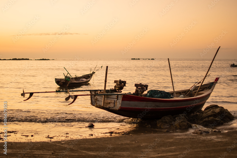 Two traditional wooden boats in a bright orange sunset, Ngwesaung, Myanmar Two traditional wooden boats in a bright orange sunset, Ngwesaung, Myanmar
