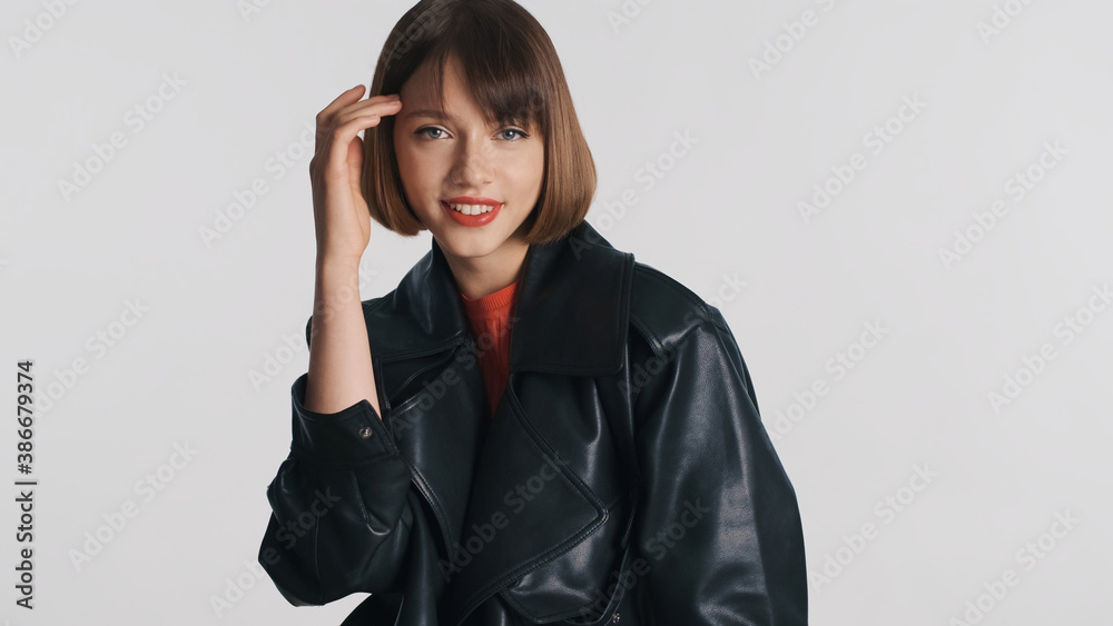Pretty smiling girl with red lips wearing leather jacket happily looking in camera isolated on white background. Fashion girl Pretty smiling girl with red lips wearing leather jacket happily looking in camera isolated on white background. Fashion girl