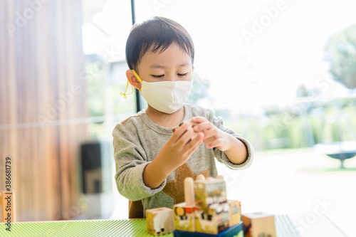 Asian toddler boy playing toy block in day care school.3.5 years old boy child wearing face mask in Day care.Covid-19 coronavirus.Nursery.Social distancing in school kid.Back to school.New normal.