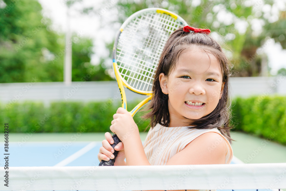 Little tennis player play tennis in court on summer.Confident asian child  girl lose fist tooth