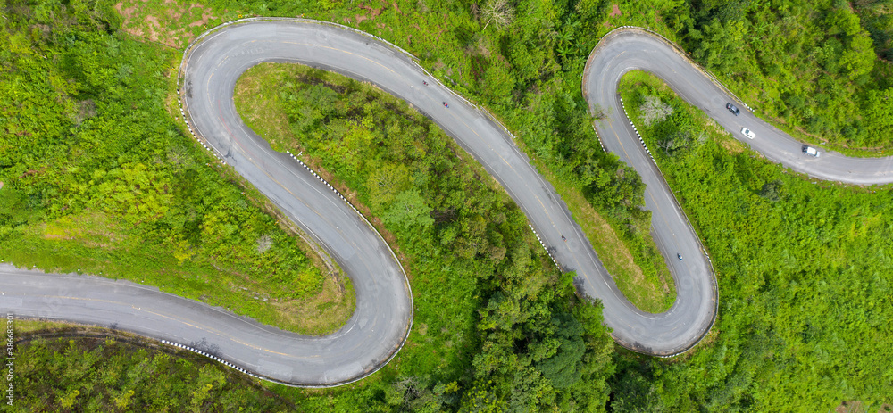 Winding road, top view of the corner Look at the beautiful aerial view of asphalt roads, highways through mountains and forests in rainy season. For traveling and driving in nature. Nan thailand