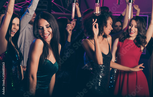 Photo of young beautiful girls dancing on party in night club wearing classy stylish dresses smiling relaxing together