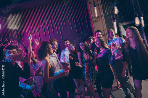 Nice attractive cheerful crowd dancing having fun celebratory corporate event newyear in dark night music club indoors with neon lights