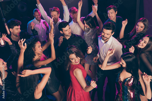 Attractive elegant cheerful crowd dancing having fun enjoying celebratory corporate event in dark night music club indoors