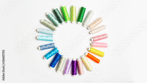 Bilde på lerret Spools of colored thread laid out in a circle on the white background with copy