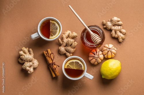 Natural cold and flu home remedies: hot tea cups with lemon, honey, ginger and garlic to boost immune system. Natural healthy food ingredients for immunity stimulation and against viruses. Top view.