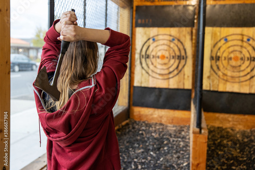 Young girl throws an axe at a target in an axe throwing range photo