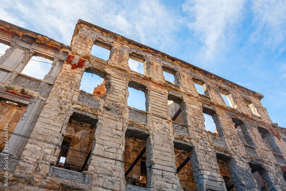 During the Yugoslavian wars destroyed building in the city center of Mostar under a blue sky with clouds. Photographed with frog perspective. Bosnia-Herzegovina.