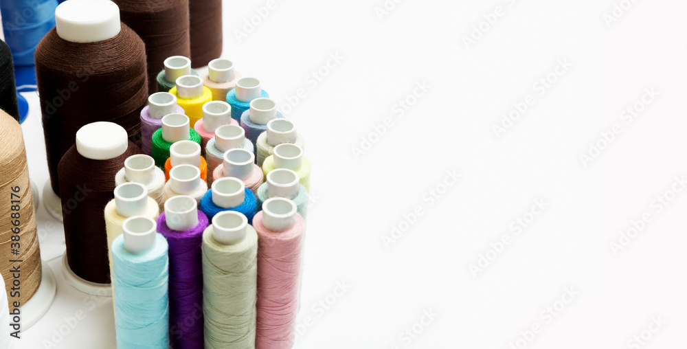 many small and large multicolored spools for sewing machine on the white background with copy space.