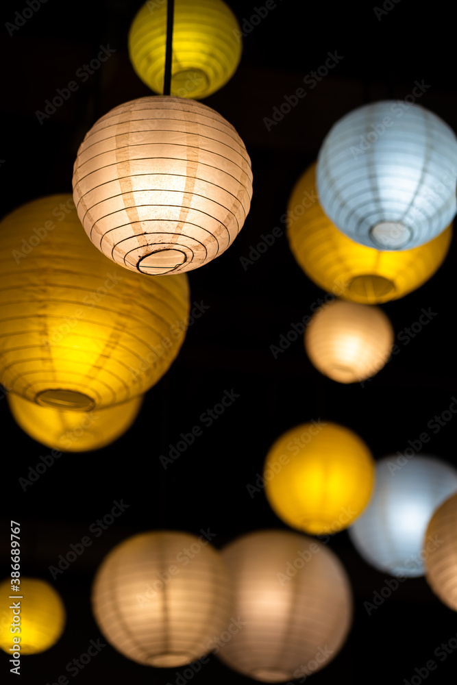 Obraz premium Group of colorful sphere paper lighting lamp on black background, background and texture photo. Selective focus at some piece of the lamp surface.