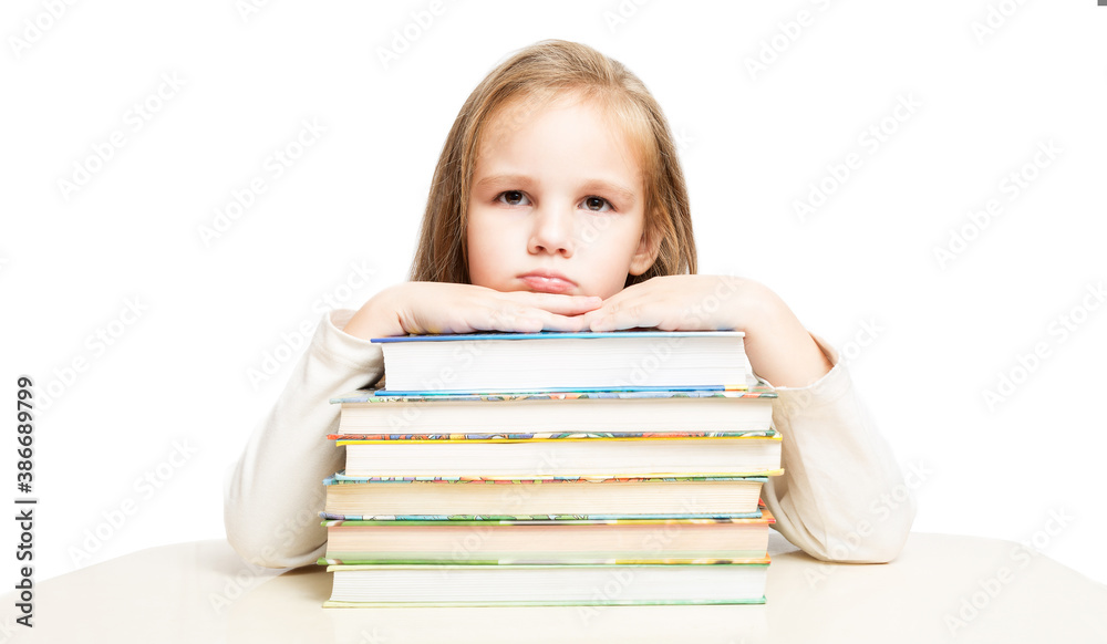 little beautiful preschooler girl sitting at a table over a pile of books tired and sad on a white background. front view. little beautiful preschooler girl sitting at a table over a pile of books tired and sad on a white background. front view.