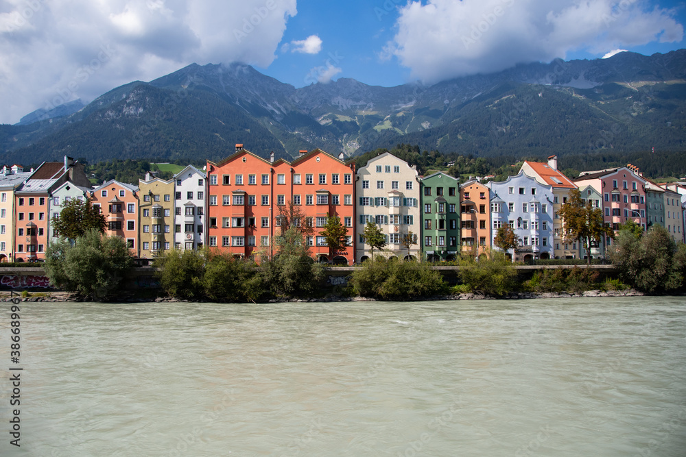 Colorful apartment buildings in Innsbruck with the river Inn and mountains in the background