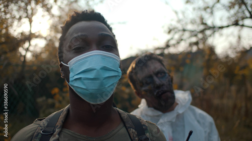 Foto Post-apocalyptic african soldier in safety mask with zombie on background