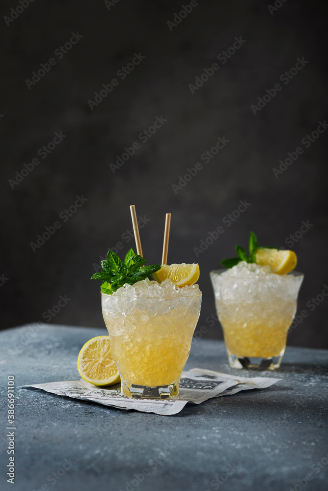 Fototapeta premium ellow cocktail with lemon, mint and crushed ice