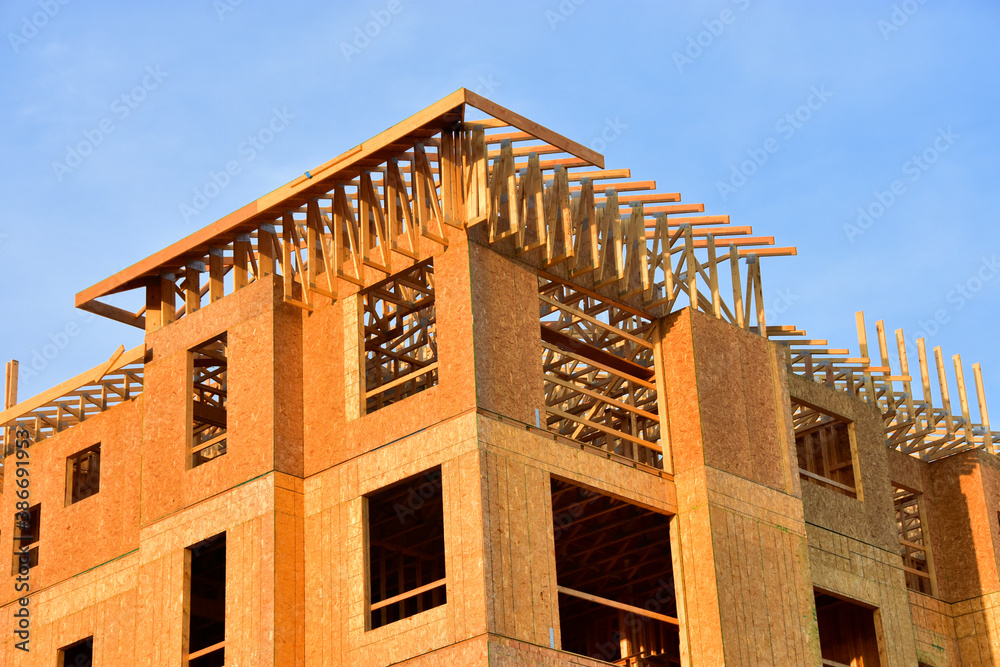 Low angle view of wood frame multi story residential structure under construction.