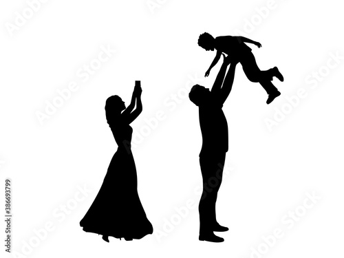 Silhouettes mother takes pictures on phone and father throws son up