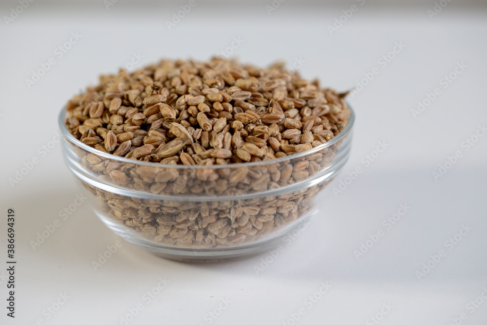 Wheat grain in a bowl, and scattered on the table, close-up. Wheat grain in a bowl, and scattered on the table, close-up.