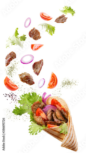 Doner kebab or shawarma with ingredients floating in the air : beef meat, lettuce, onion, tomatos, spice. White background. Copy space.