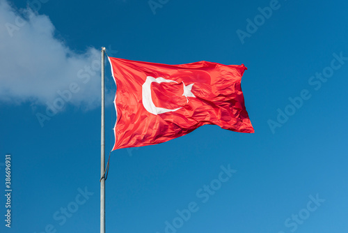 Turkish national flag waving in blue sky.