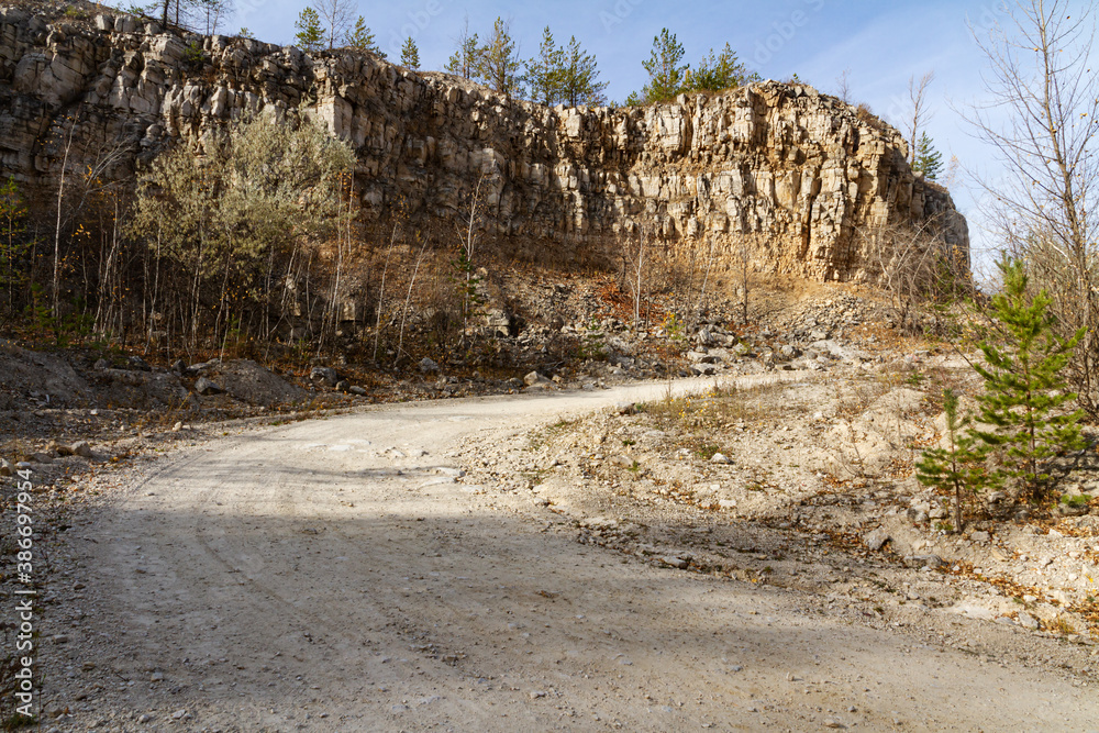 Road under destroyed rocks in an old quarry