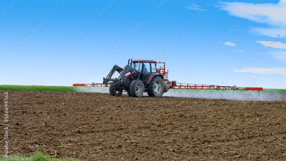 Obraz premium tracteur agricole répandant l'insecticide sur le champ