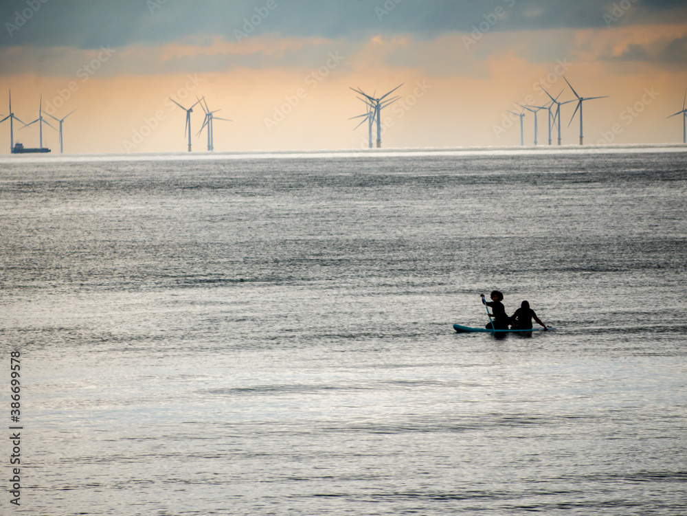 Naklejka premium Paddling a canoe past a marine windfarm