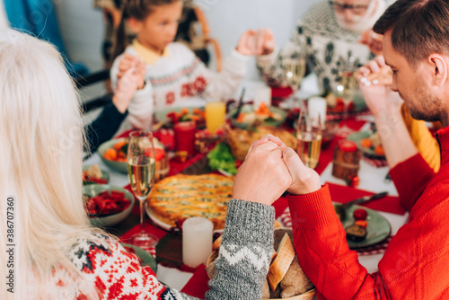 Selective focus of woman and man holding hands near family, sitting at table photo