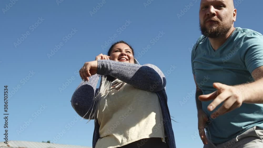 Body positive fat friends enjoy life and sunny weather. Two young happy people dance on background of bright blue sky. Music and copy space concept. man with tattoo and a woman with dreads dancing.