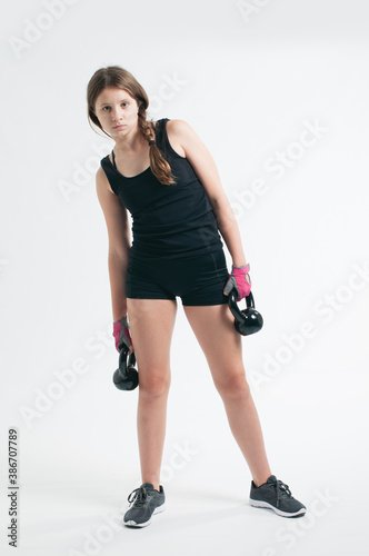 tenage girl doing excercise with the kettlebell over the white background © 90783759