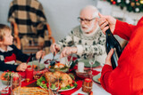 Selective focus of man opening champagne bottle near family and festive table