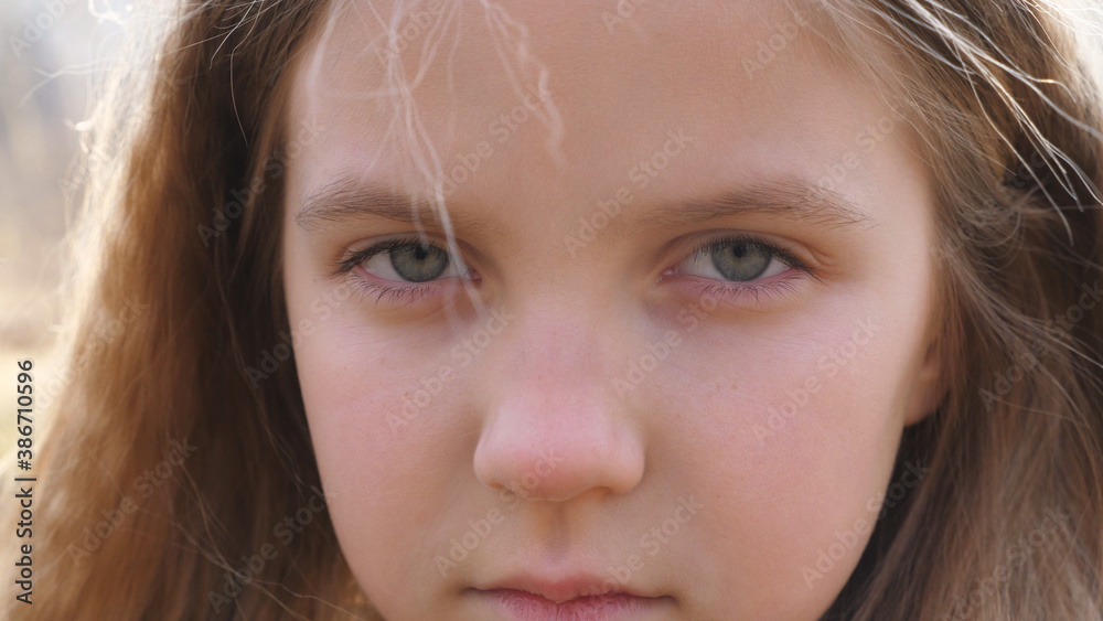 Close up upset female face of little kid looking into camera with a disappointing sight. Facial expression of small girl with blonde hair. Unhappy gaze of despairing child Close up upset female face of little kid looking into camera with a disappointing sight. Facial expression of small girl with blonde hair. Unhappy gaze of despairing child