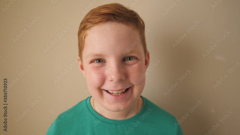 Happy joyful red-haired boy looking into camera and laughing indoor. Close up emotions of little smiling kid with glad expression on his face. Portrait of small male ginger child with freckles inside Happy joyful red-haired boy looking into camera and laughing indoor. Close up emotions of little smiling kid with glad expression on his face. Portrait of small male ginger child with freckles inside