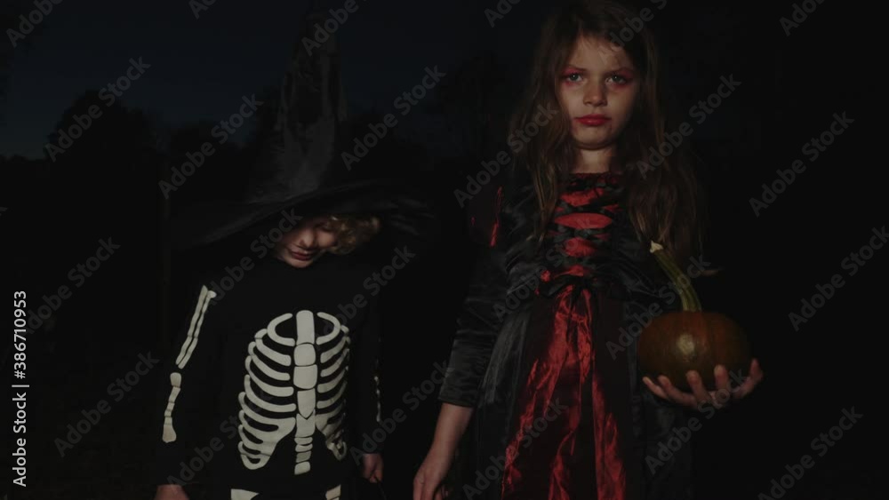 Kids in Halloween costumes walk around holding a pumpkin Kids in Halloween costumes walk around holding a pumpkin