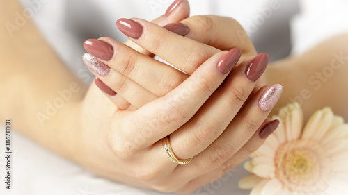 Elegant hands with fresh lilac pink manicure with daisy gerbera flower